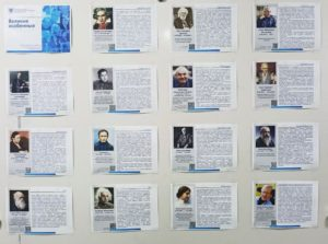 На картине изображен стенд с великими особами и с их биографией.